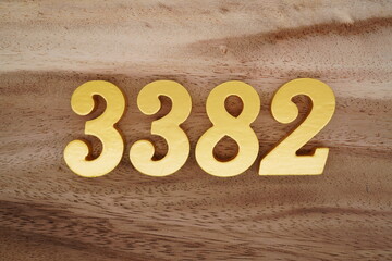 Golden Arabic numerals on a real brown and white wooden floor number 3382