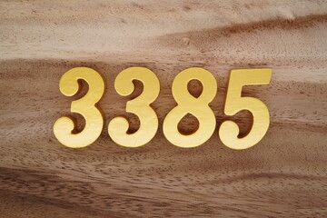 Golden Arabic numerals on a real brown and white wooden floor number 3385