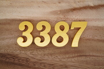 Golden Arabic numerals on a real brown and white wooden floor number 3387