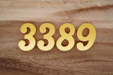 Golden Arabic numerals on a real brown and white wooden floor number 3389