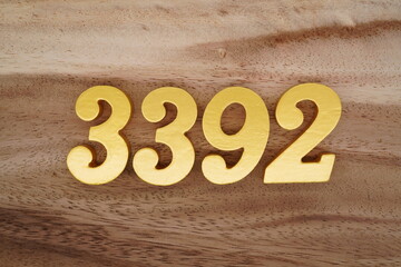 Golden Arabic numerals on a real brown and white wooden floor number 3392