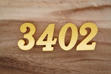 Golden Arabic numerals on a real brown and white wooden floor number 3402