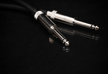 Two silver TRS connectors for the analog audio signal are placed against a black background....