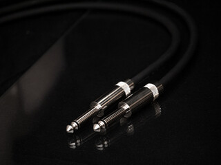Two silver TRS connectors for the analog audio signal are placed against a black background. Professional jack connectors for sound equipment. Audiophile technologies concept.