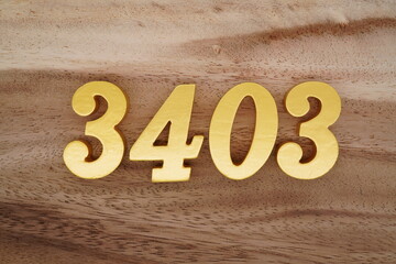 Golden Arabic numerals on a real brown and white wooden floor number 3403