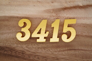 Golden Arabic numerals on a real brown and white wooden floor number 3415