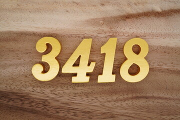 Golden Arabic numerals on a real brown and white wooden floor number 3418