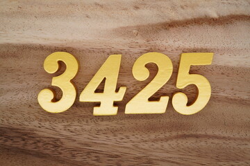 Golden Arabic numerals on a real brown and white wooden floor number 3425
