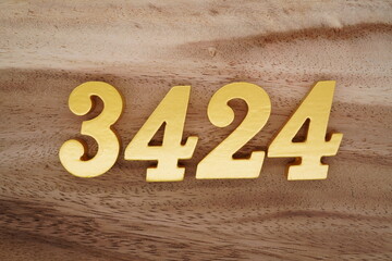 Golden Arabic numerals on a real brown and white wooden floor number 3424