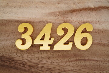 Golden Arabic numerals on a real brown and white wooden floor number 3426