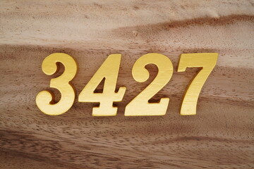 Golden Arabic numerals on a real brown and white wooden floor number 3427