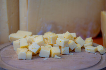 Selective focus of diced cheese on the wooden plank, Blocks of young cheese on chopping wood display on the market in Netherlands