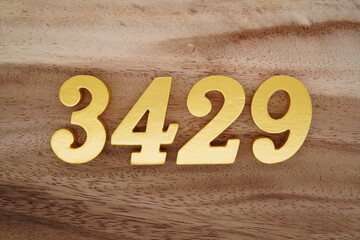 Golden Arabic numerals on a real brown and white wooden floor number 3429