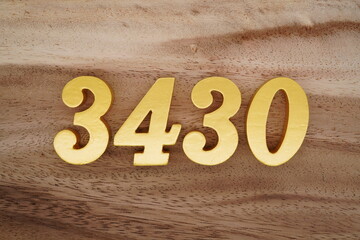 Golden Arabic numerals on a real brown and white wooden floor number 3430
