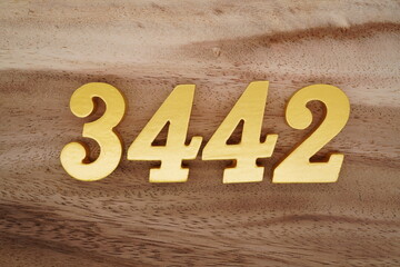 Golden Arabic numerals on a real brown and white wooden floor number 3442