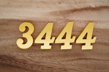 Golden Arabic numerals on a real brown and white wooden floor number 3444