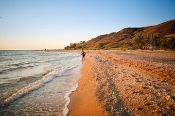 Cute european child teen girl run along the beach by the sea, happy childhood and freedom. Plus size kid, overweight and sports by the sea