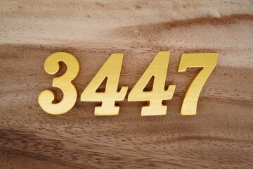 Golden Arabic numerals on a real brown and white wooden floor number 3447