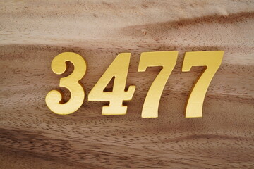Golden Arabic numerals on a real brown and white wooden floor number 3477