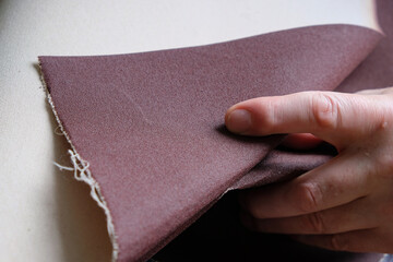 Male hand with sandpaper. Sandpaper on the fabric basis. Copy space.