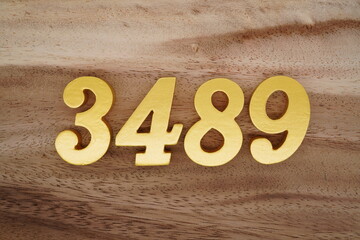 Golden Arabic numerals on a real brown and white wooden floor number 3489