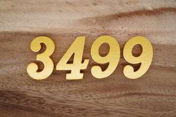 Golden Arabic numerals on a real brown and white wooden floor number 3499