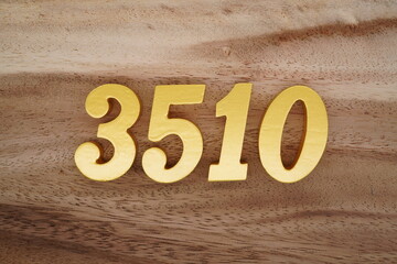 Golden Arabic numerals on a real brown and white wooden floor number 3510