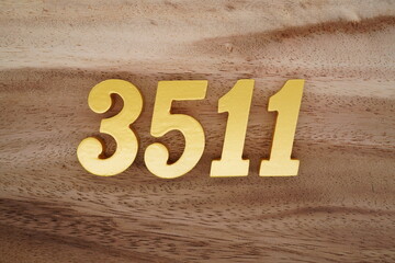 Golden Arabic numerals on a real brown and white wooden floor number 3511