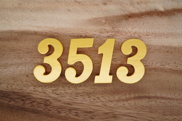 Golden Arabic numerals on a real brown and white wooden floor number 3513