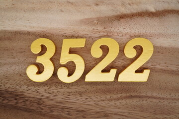 Golden Arabic numerals on a real brown and white wooden floor number 3522