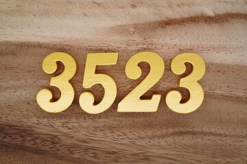 Golden Arabic numerals on a real brown and white wooden floor number 3523
