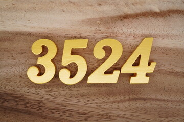 Golden Arabic numerals on a real brown and white wooden floor number 3524