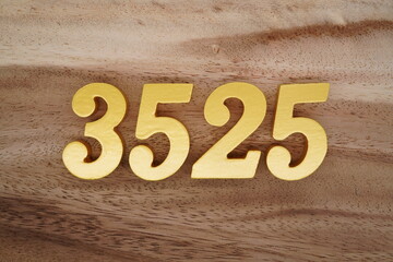 Golden Arabic numerals on a real brown and white wooden floor number 3525