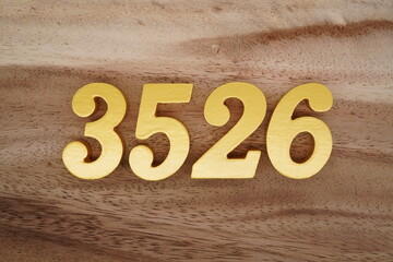 Golden Arabic numerals on a real brown and white wooden floor number 3526