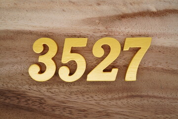 Golden Arabic numerals on a real brown and white wooden floor number 3527