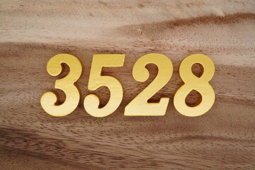 Golden Arabic numerals on a real brown and white wooden floor number 3528