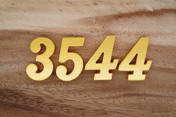 Golden Arabic numerals on a real brown and white wooden floor number 3544