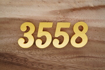 Golden Arabic numerals on a real brown and white wooden floor number 3558