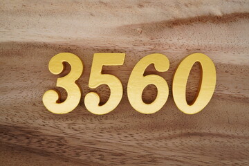 Golden Arabic numerals on a real brown and white wooden floor number 3560