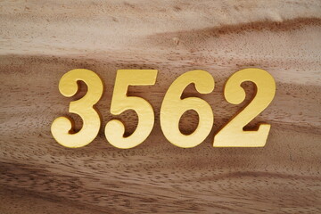 Golden Arabic numerals on a real brown and white wooden floor number 3562