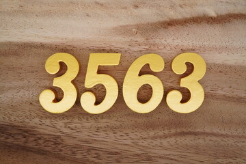Golden Arabic numerals on a real brown and white wooden floor number 3563