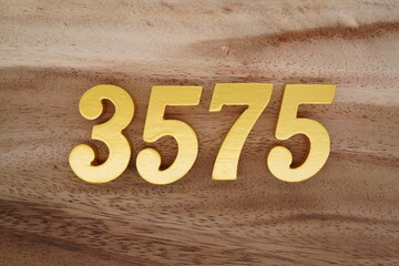 Golden Arabic numerals on a real brown and white wooden floor number 3575