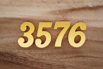 Golden Arabic numerals on a real brown and white wooden floor number 3576
