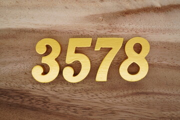 Golden Arabic numerals on a real brown and white wooden floor number 3578