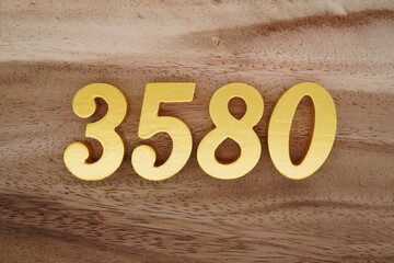 Golden Arabic numerals on a real brown and white wooden floor number 3580