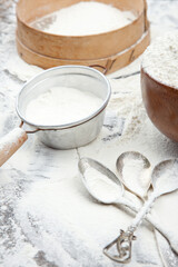 Obraz na płótnie Canvas Flour in a bowl and a sieve. Photo of food on a light background.