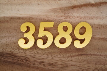 Golden Arabic numerals on a real brown and white wooden floor number 3589