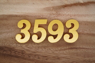 Golden Arabic numerals on a real brown and white wooden floor number 3593