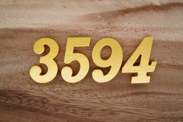 Golden Arabic numerals on a real brown and white wooden floor number 3594