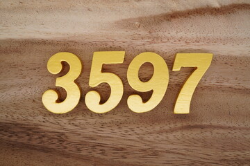 Golden Arabic numerals on a real brown and white wooden floor number 3597